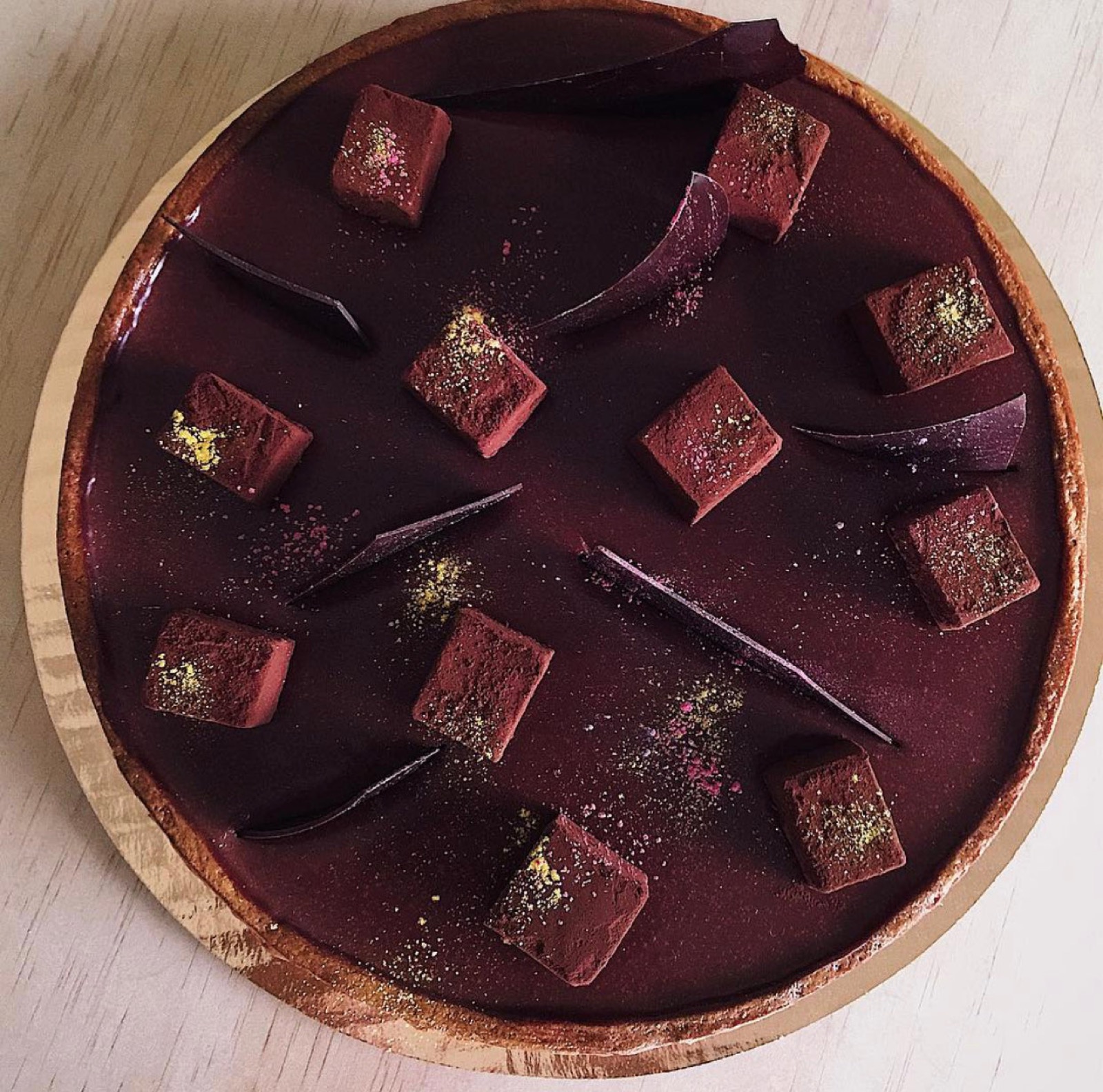 Dark chocolate and cacao caramel tart with truffle cubes and botanical dust