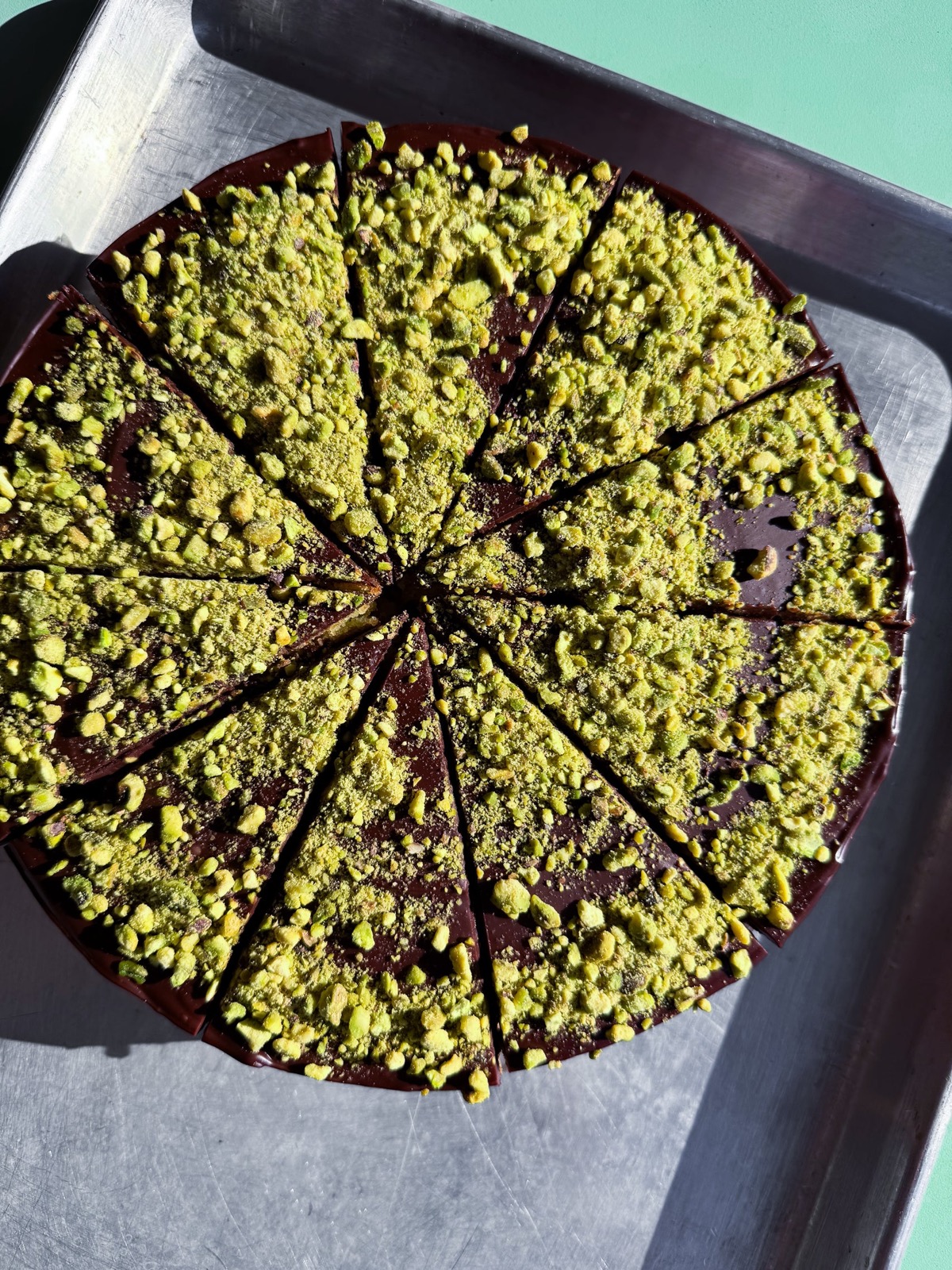 Pistachio cake with dark chocolate ganache, dusted with crushed pistachio